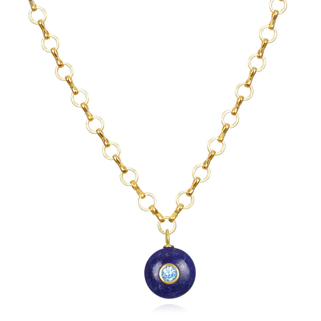 A delicate gold chain necklace with a round deep blue lapis lazuli pendant and a central light blue topaz gemstone