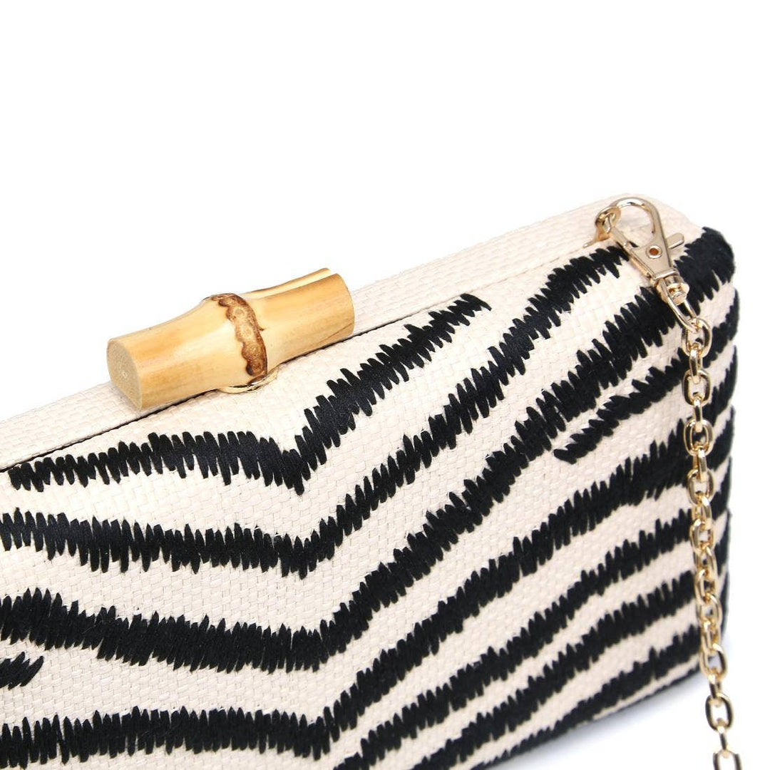 Dorit clutch is a black and white zigzag patterned bag with a bamboo clasp and gold-tone chain strap