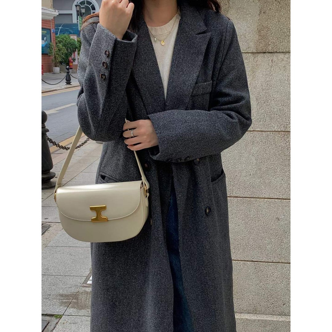 Cream-colored leather shoulder bag with gold-tone t-shaped clasp designed for crossbody use