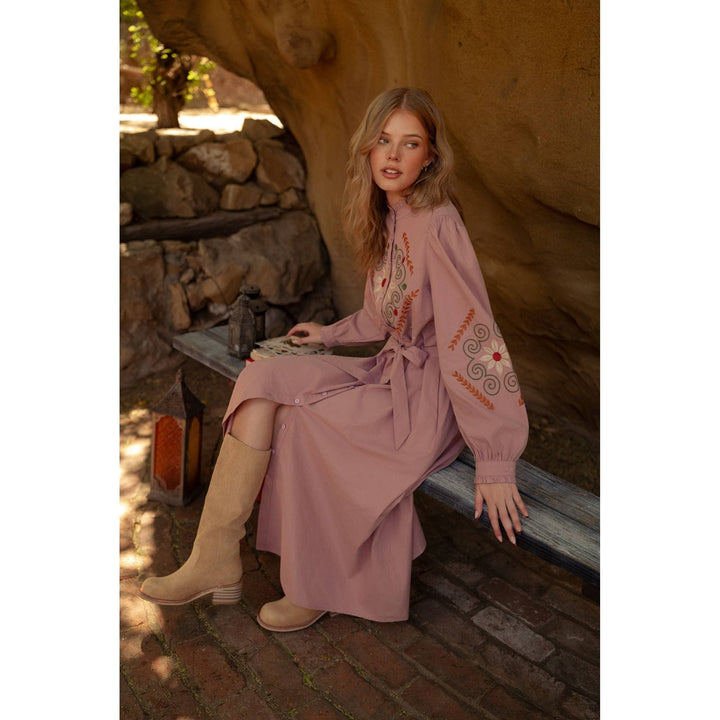A soft pink embroidered shirtdress with long sleeves featuring intricate orange and red patterns on neckline and sleeves