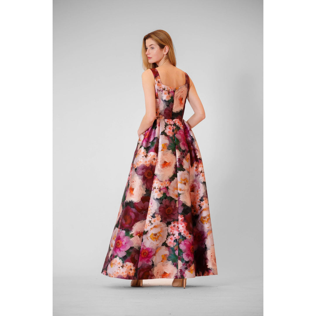 A woman wearing a mikado autumn floral gown with a flowing floor-length floral pattern in pink burgundy and cream