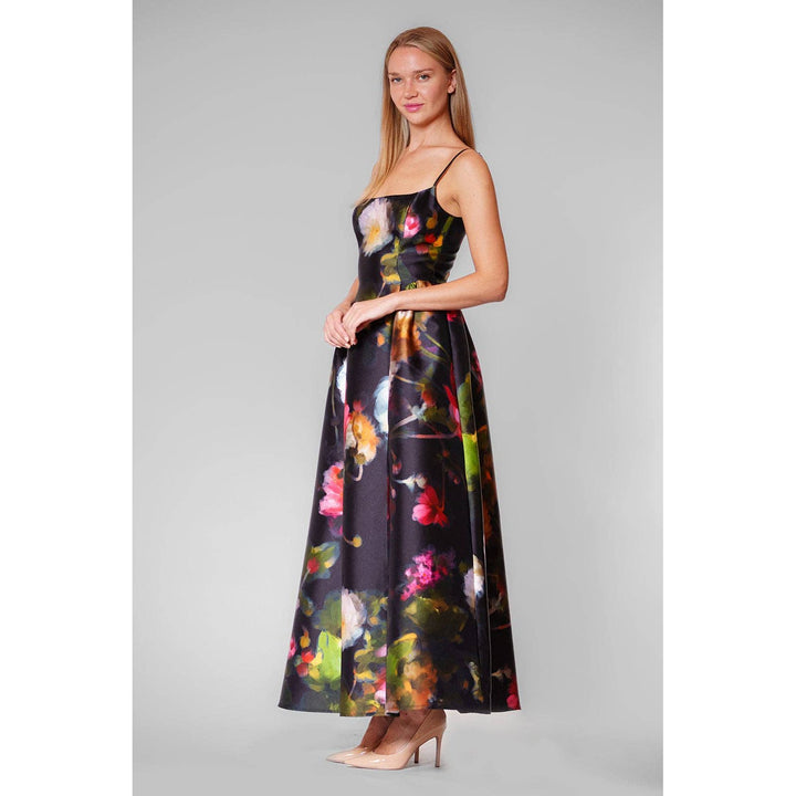 A woman wears a black satin midnight garden gown with vibrant pink green and yellow floral patterns