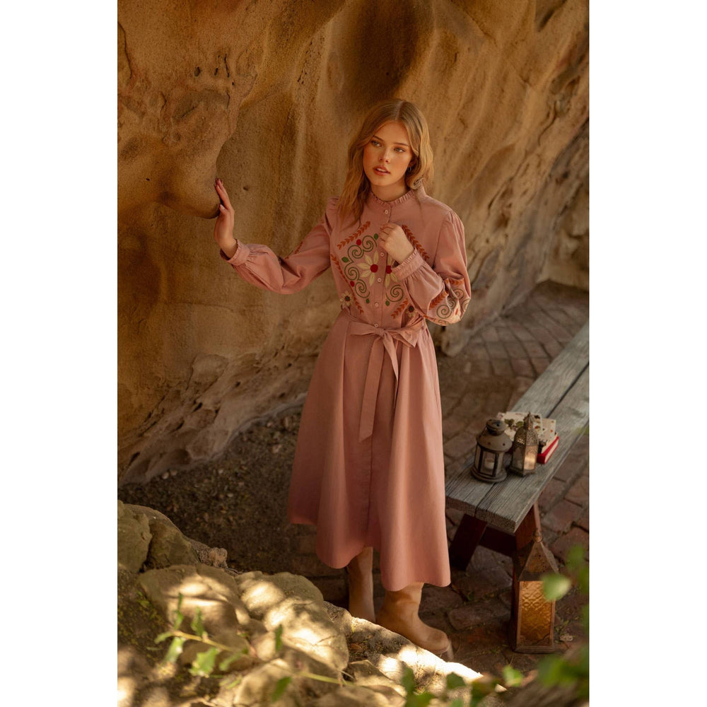 A soft pink embroidered shirtdress with long sleeves and a matching belt tied at the waist