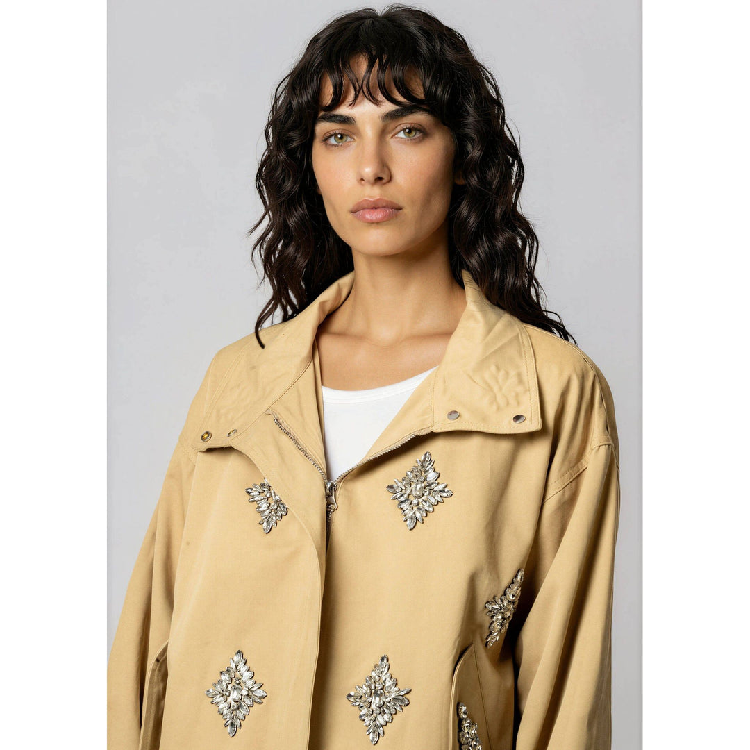 Beige crystal embellished utility jacket with silver leaf shaped embellishments on a trench coat style design