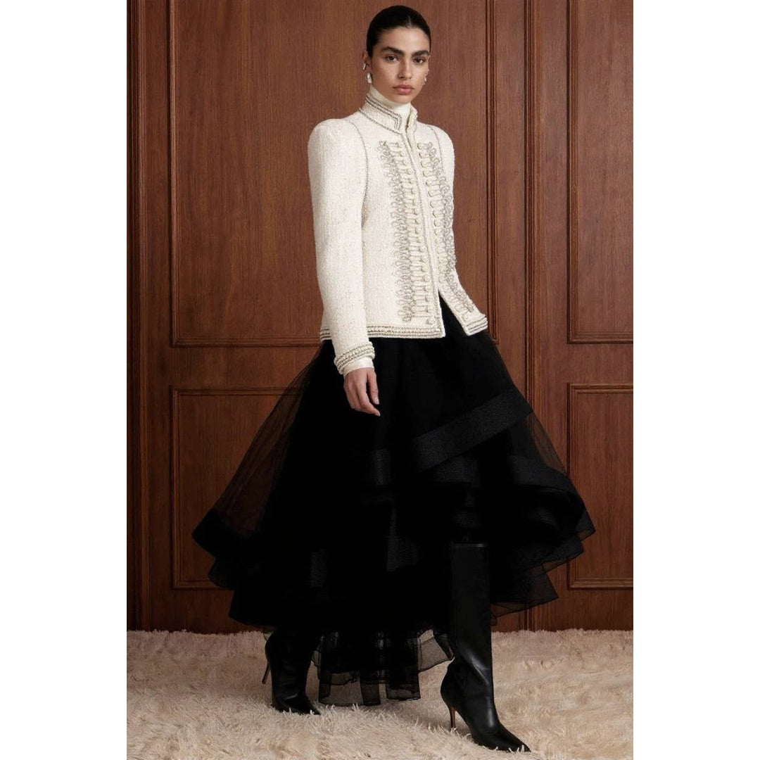 A cream-colored bouclé military jacket with intricate silver embroidery and pearl embellishments on the front and cuffs