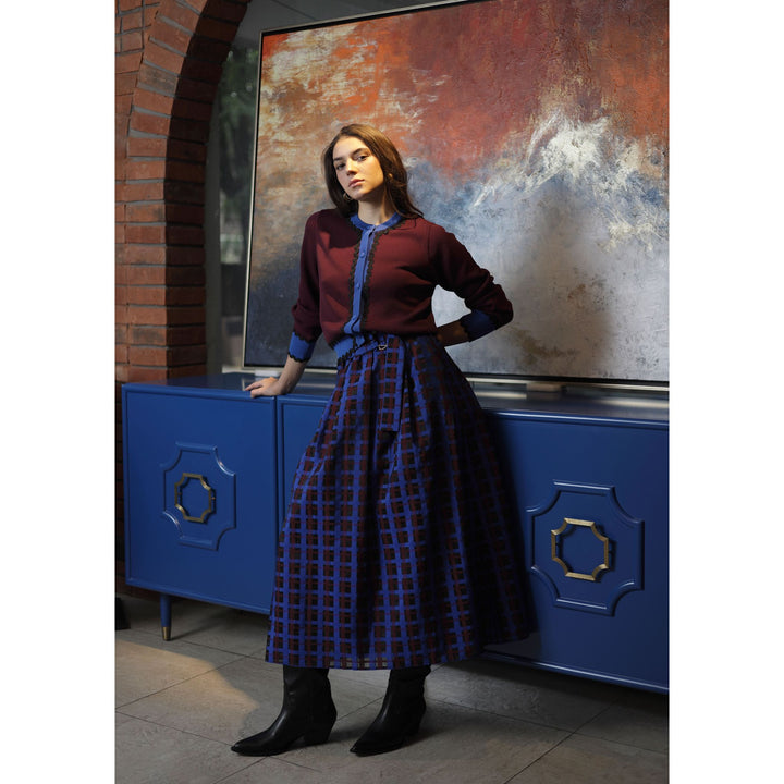 A woman wears a Diana cardigan in maroon with blue trim over a blue blouse paired with a navy and burgundy plaid skirt