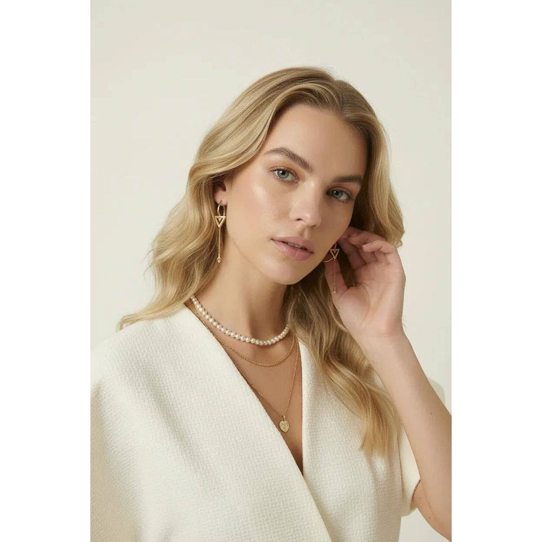 Gold triangle drop earrings with delicate chain detailing complementing textured wrap top look