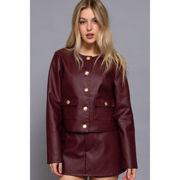 Burgundy cropped jacket in maroon faux leather with gold-tone buttons and flap pockets