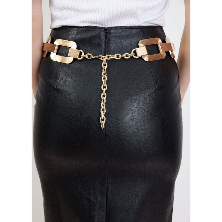 Large link chain belt gold toned with rectangular metal buckles and chain detail worn over black faux leather pants