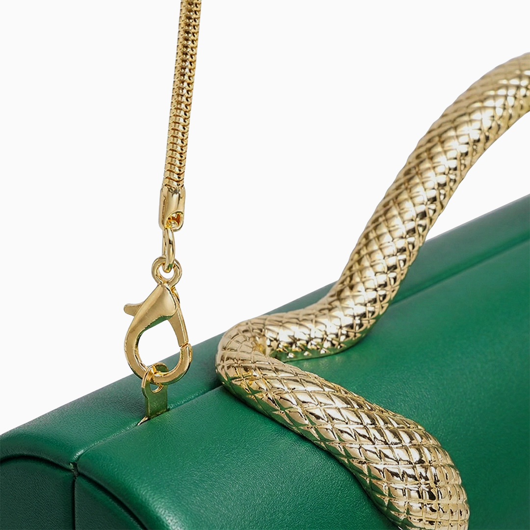 A green leather maren handbag with a gold-toned snake-shaped textured handle resting on its surface