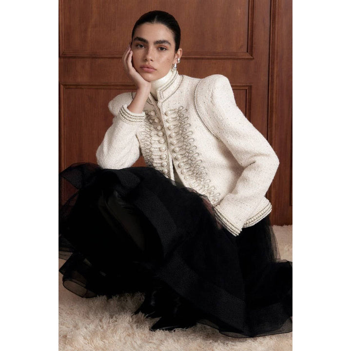 A cream-colored bouclé pearl embellished military jacket with silver-toned buttons and a high collar