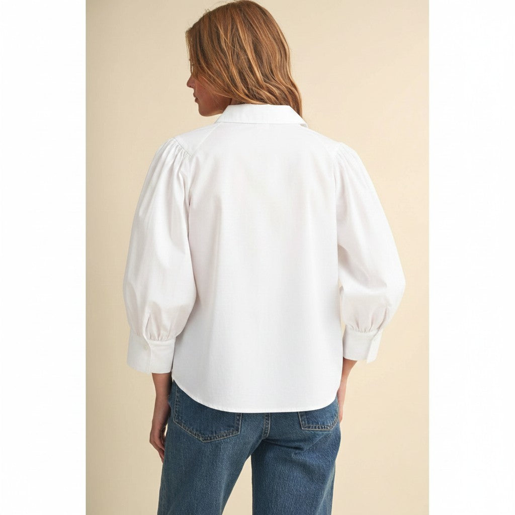 Back view of The Pearl Pagoda Camille white cotton buttondown top with long sleeves and pleated details on a model.