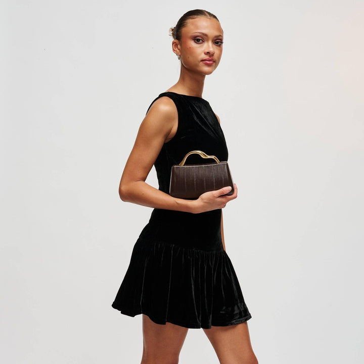 Model holding The Pearl Pagoda Nichelle Clutch in espresso brown with a sculptural gold handle and embossed texture.