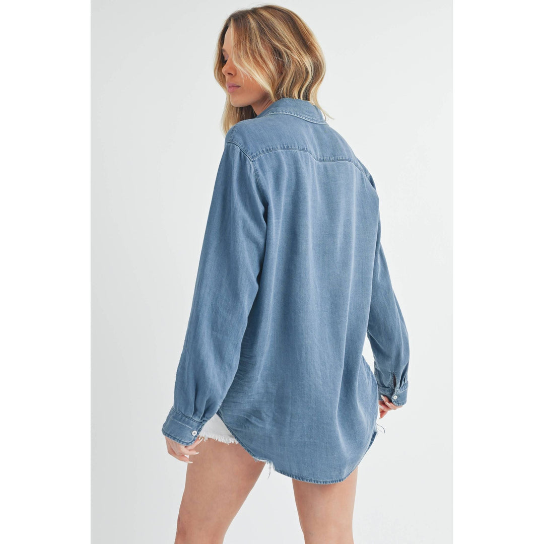The Pearl Pagoda Ottavia denim top in a relaxed fit with a raw shirttail hem, shown from the back on a model.