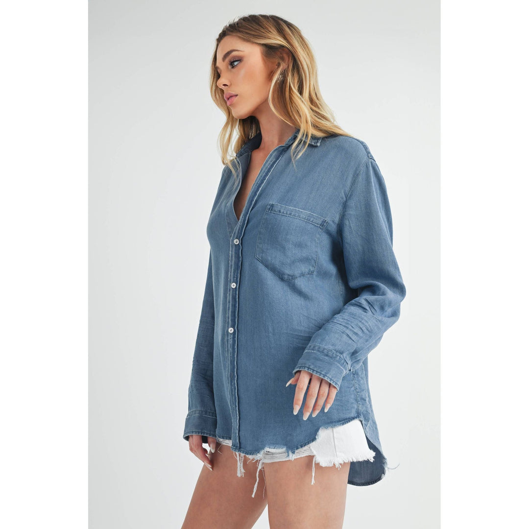 The Pearl Pagoda Ottavia denim top with a relaxed fit, chest pocket, and raw distressed shirttail hem on a model.