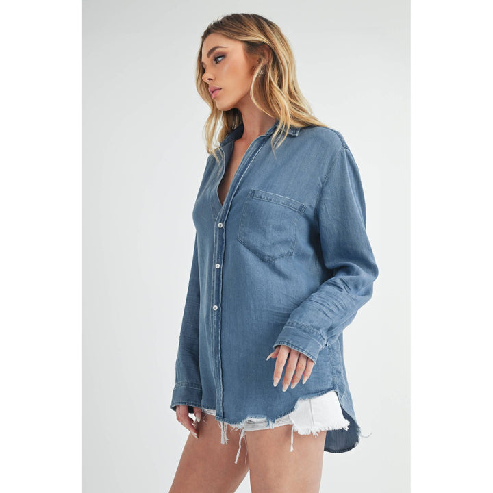 The Pearl Pagoda Ottavia denim top with a relaxed fit, chest pocket, and raw distressed shirttail hem on a model.