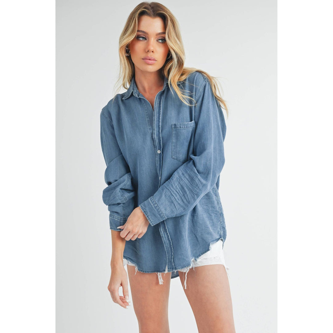The Pearl Pagoda Ottavia denim top with long sleeves, chest pocket, and raw shirttail hem on a blonde model