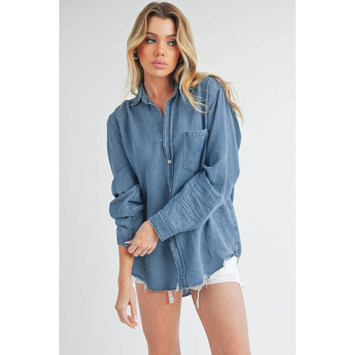 The Pearl Pagoda Ottavia denim top with long sleeves, chest pocket, and raw shirttail hem on a blonde model