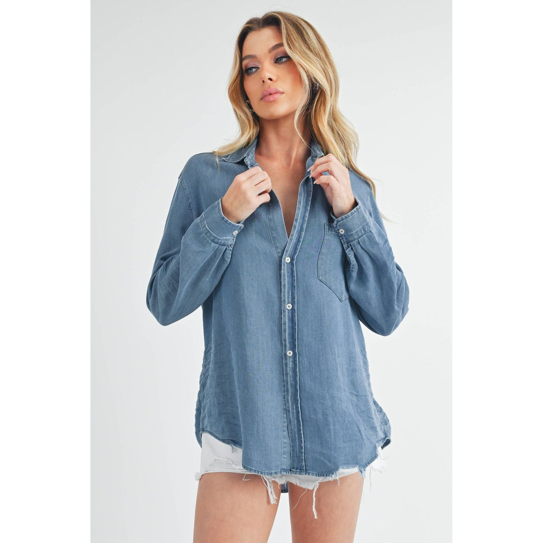 The Pearl Pagoda Ottavia denim top with a relaxed fit, chest pocket, and raw hem worn by a blonde model.