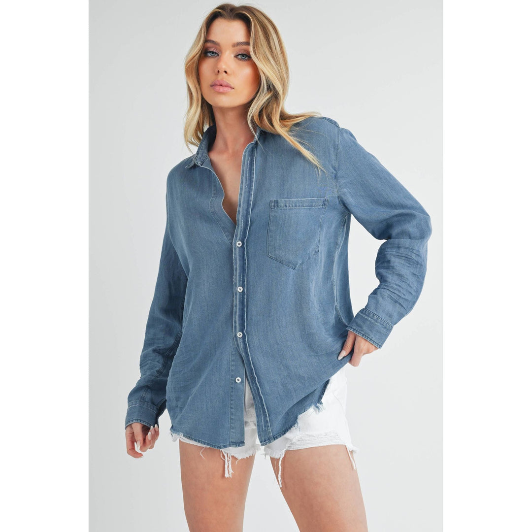 The Pearl Pagoda Ottavia denim top with a relaxed fit, chest pocket, and raw hem worn by a blonde model.